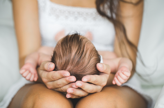 Mujer con bebe en los brazos y alopecia postparto