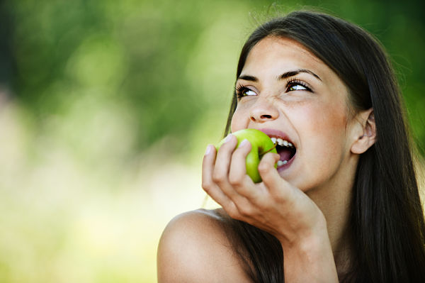 Mujer comiendo fruta, uno de los alimentos clave para el cabello